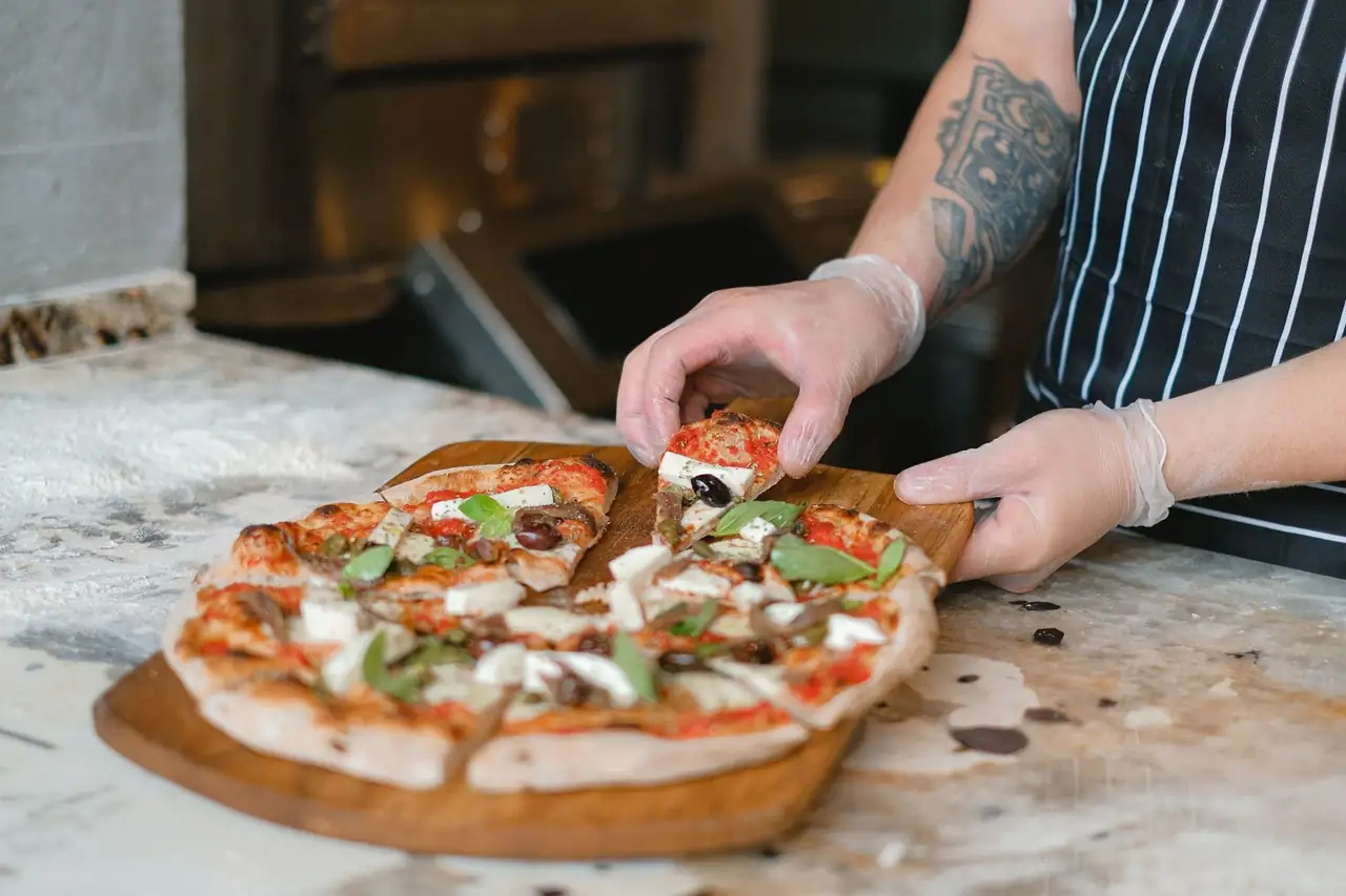 Chef slicing fresh pizza
